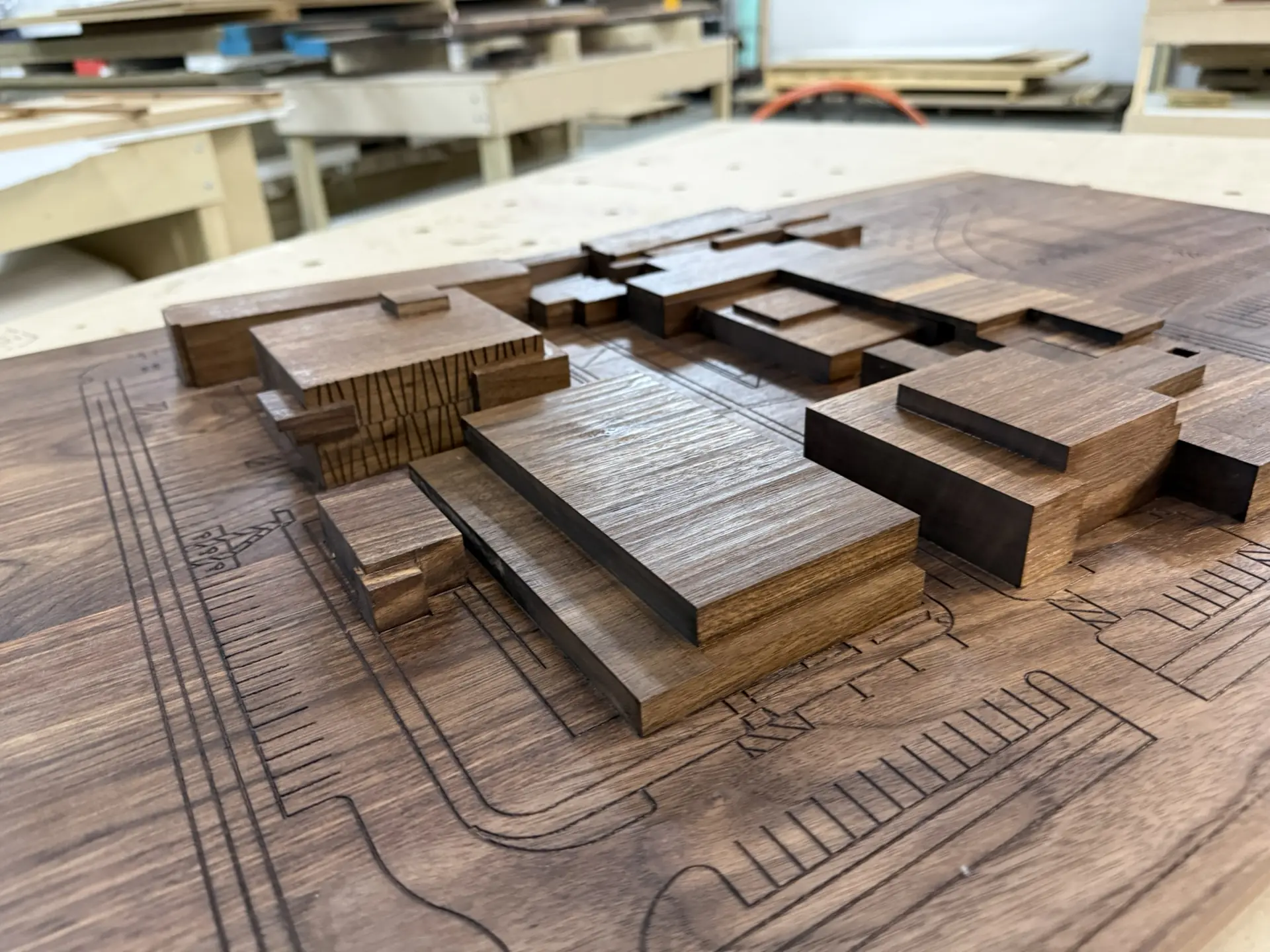 A walnut architectural site model, building masses standing on a routed site plan