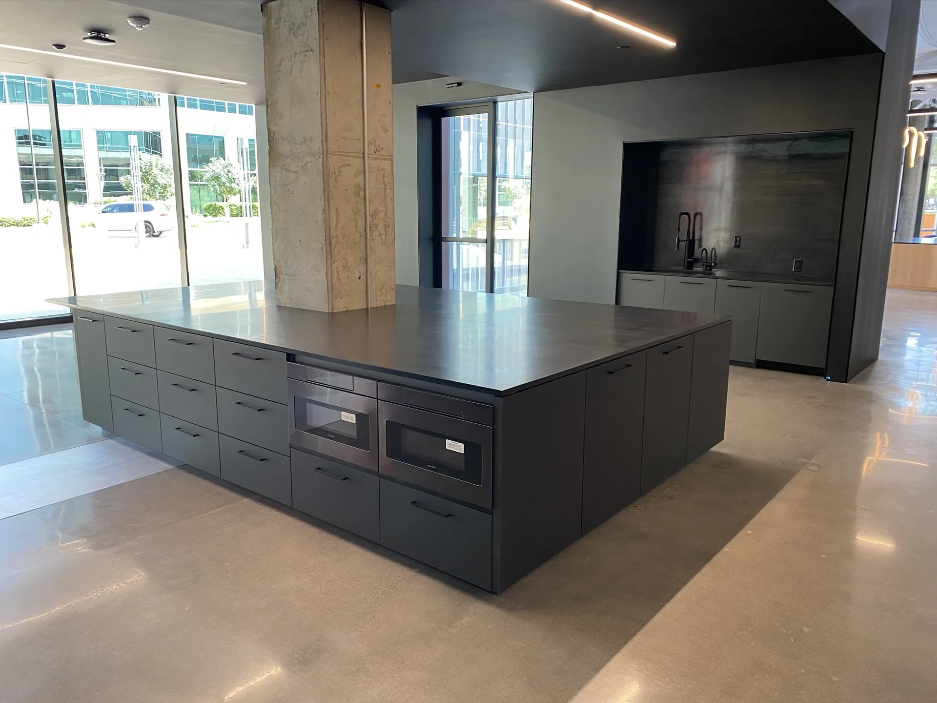 A long black casework island with integrated appliances in a commercial interior