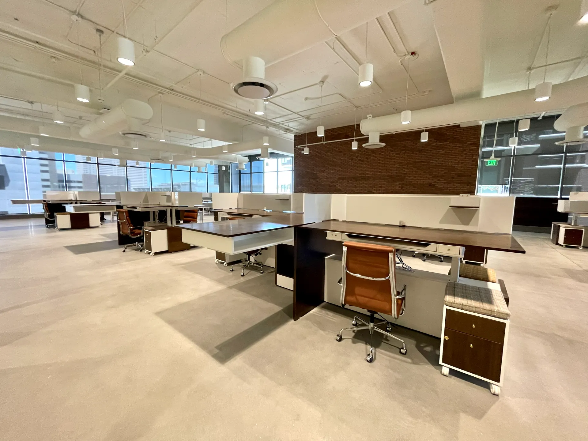 Open-plan office with matching height-adjustable desks, monitor arms and rolling pedestals