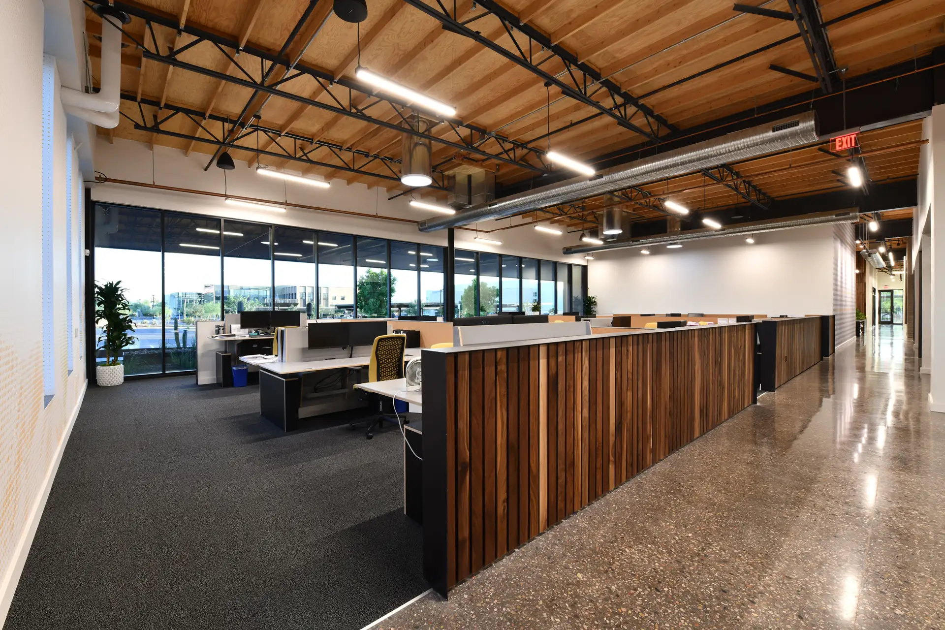 A reception desk with a walnut slat front on an open office floor under exposed timber trusses