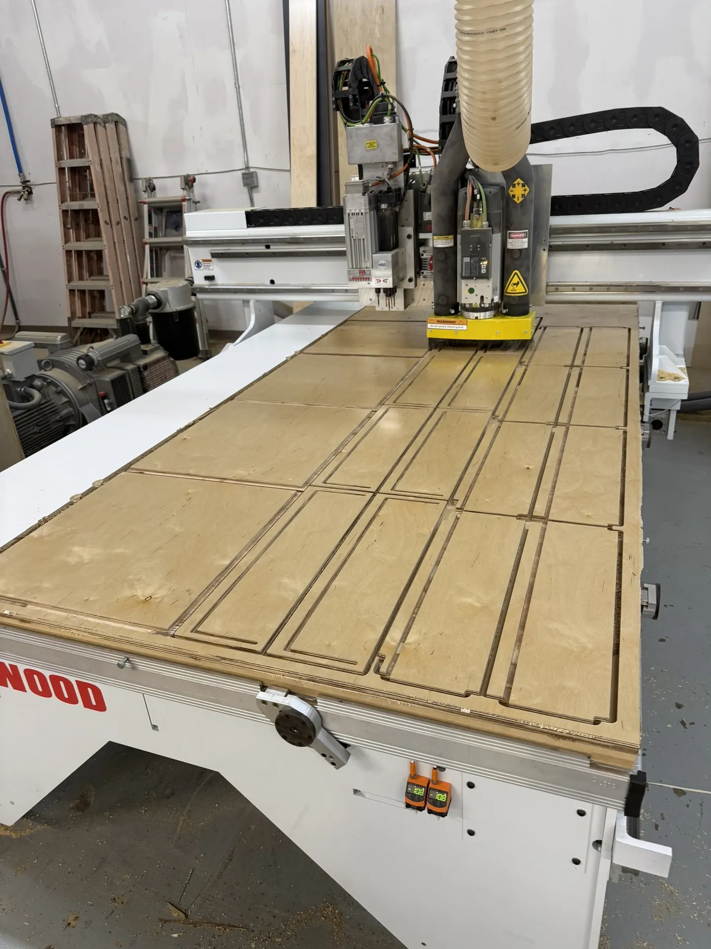 A sheet of plywood on the Thermwood CNC table with cabinet parts cut and ready to lift out