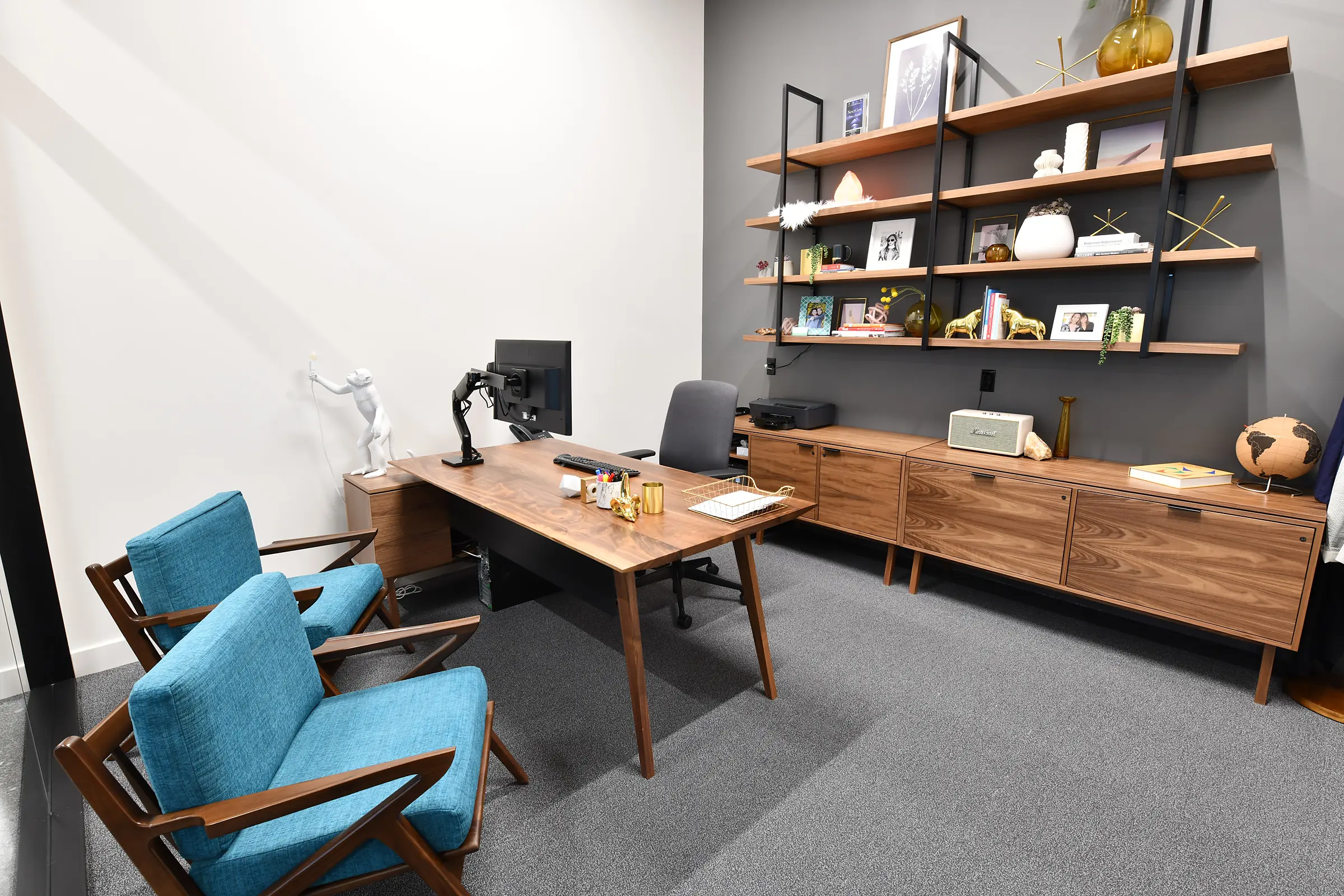 A walnut executive desk and matching credenza with floating shelves in a private office